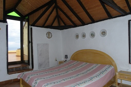 Schlafzimmer mit hoher Balkendecke und Marmorheizung